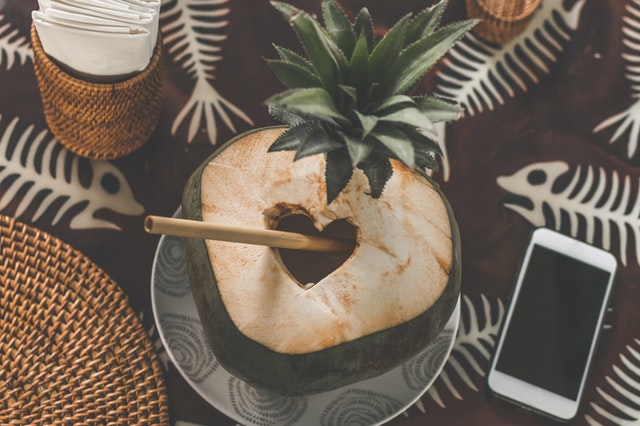 Coconut drink with a bamboo-style straw near a smartphone